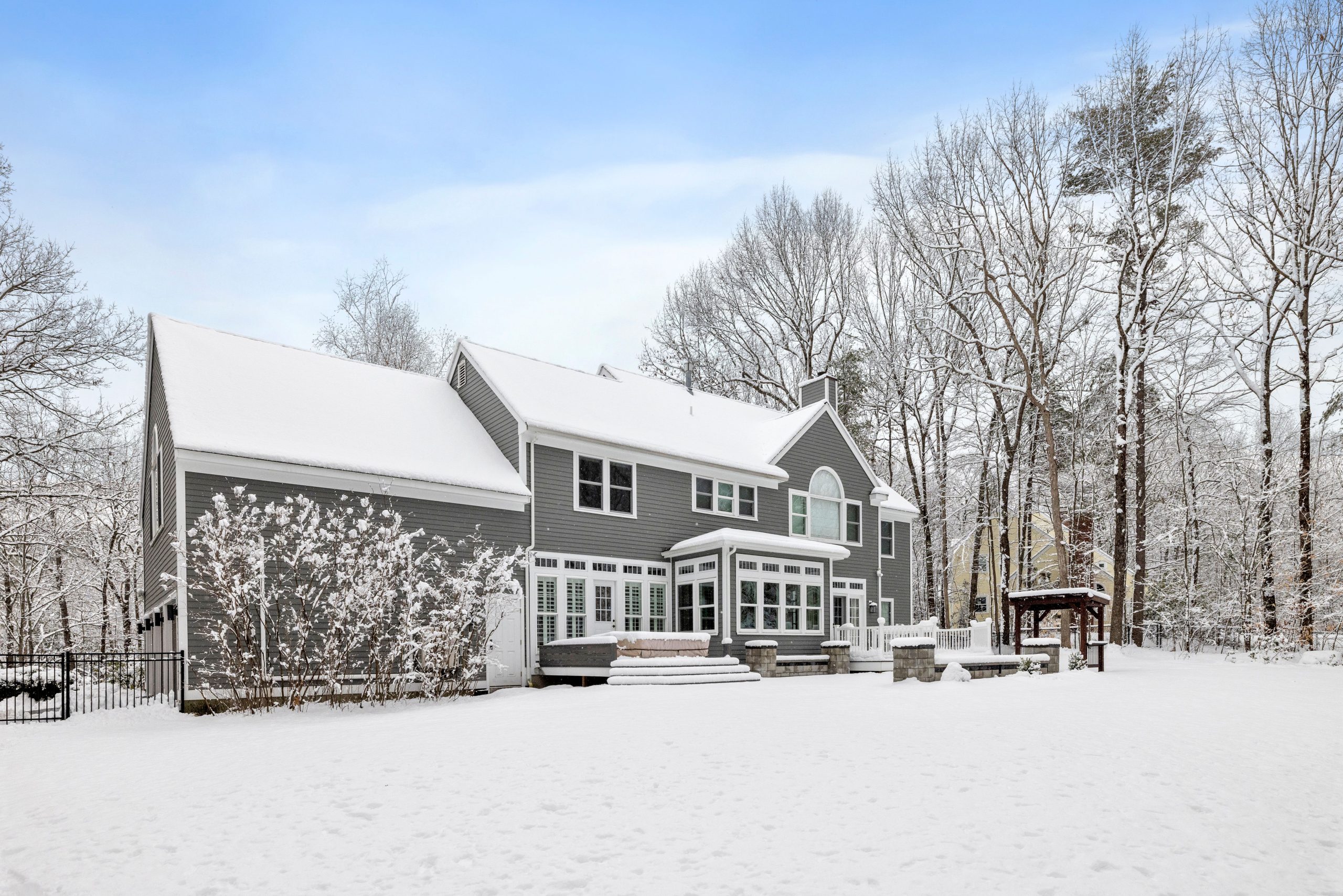 a house sitting in the snow outside in front of trees